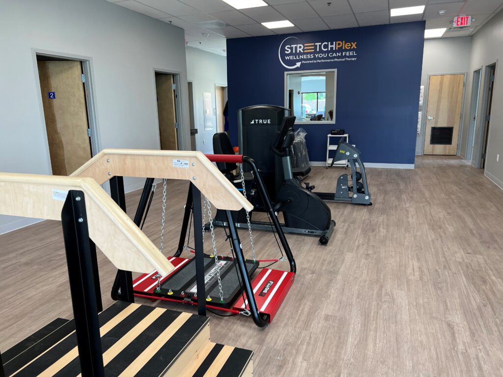 A modern physical therapy office with various exercise equipment including a treadmill and an adjustable therapy stair set.